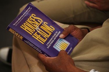 Students hands holding a book titled Housing of Healing